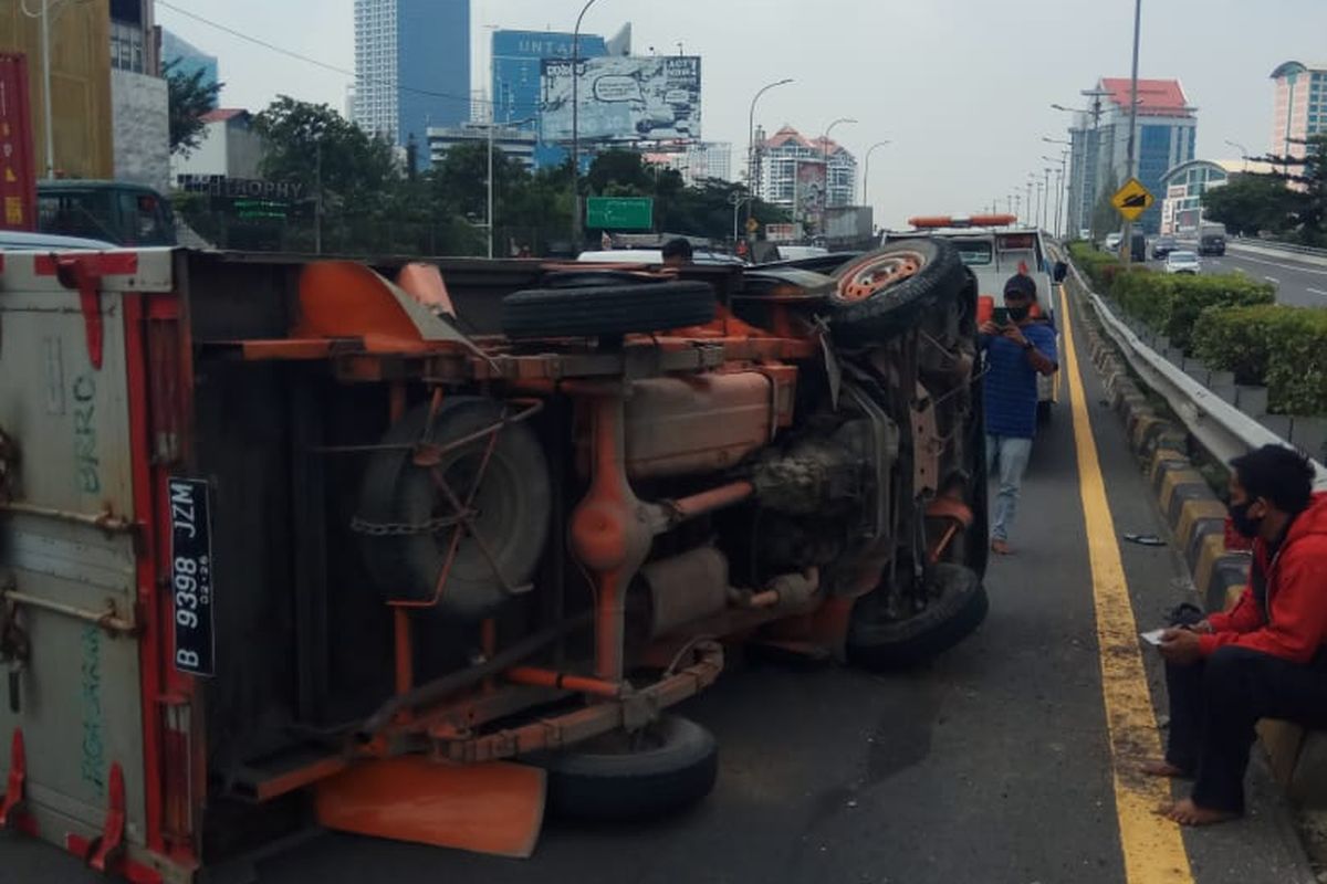 Sebuah mobil boks yang sedang melintas di ruas tol dalam kota kawasan Grogol, Jakarta Barat terguling pada Jumat (5/3/2021) siang, sekitar pukul 12.00 WIB.