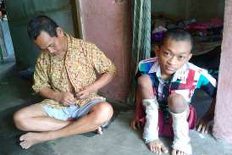 Khoirul alias Irul (kanan) bersama dengan sang ayah Rochmad yang sama-sama mengalami kelumpuhan di rumahnya, Senin (21/11/2016).