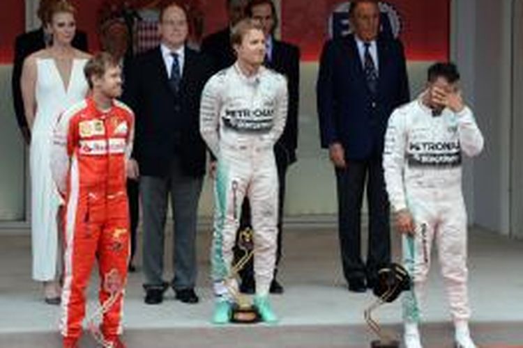 Pebalap Mercedes asal Jerman, Nico Rosberg, berdiri di atas podium didampingi rekan satu timnya yang finis ketiga, Lewis Hamilton (kanan), dan pebalap Ferrari yang finis kedua, Sebastian Vettel, setelah finis pertama pada GP Monaco di Sirkuit Monte Carlo, Minggu (25/5/2015).
