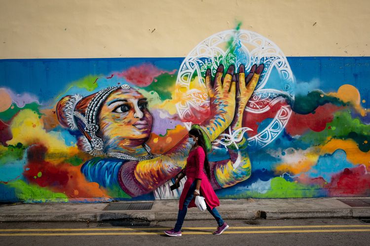 Seorang pengunjung sedang melintas di depan mural yang ada di kawasan Little India, Singapura (10/4/2021).