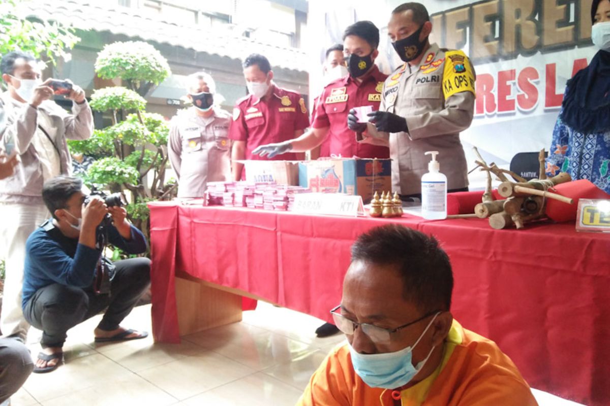 Kapolres Lamongan AKBP Miko Indrayana bersama Kasatreskrim Polres Lamongan AKP Yoan Septi Hendri saat menunjukkan barang bukti uang palsu atau uang mainan milik pelaku (kanan bawah), dalam rilis pengungkapan kasus di Mapolres Lamongan, Selasa (30/3/2021).