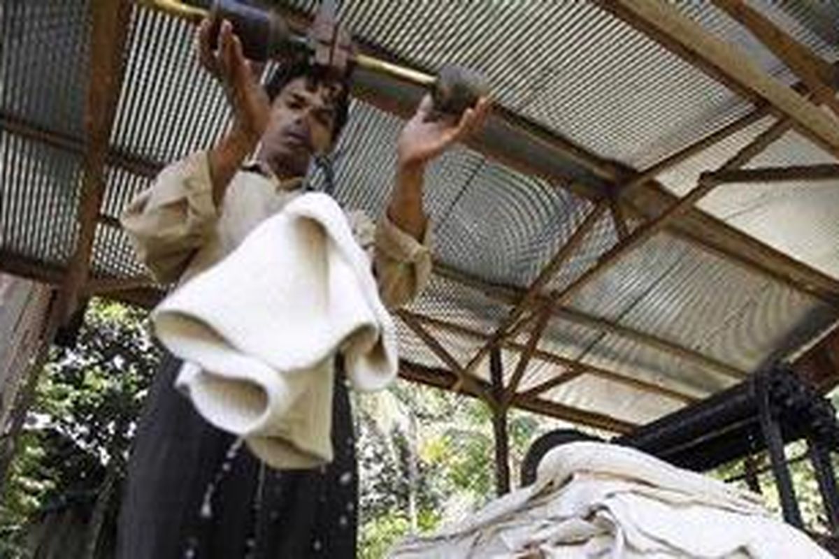 Rajuli menimbang getah karet yang akan diasapkan di rumah pengasapan karet Desa Tamiang, Kecamatan Tanta, Kabupaten Tabalong, Kalimantan Selatan, Kamis (20/5/2010).