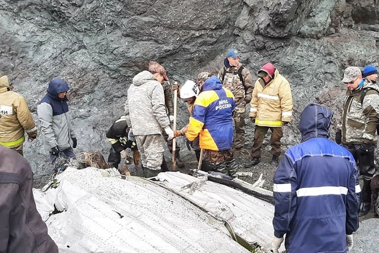 Foto ini dirilis oleh layanan pers Kementerian Situasi Darurat Rusia pada Rabu, 7 Juli 2021, menunjukkan pekerja Kementerian Situasi Darurat di puing-puing pesawat Antonov An-26 yang hilang ditemukan di dekat bandara tujuannya di luar kota Palana, di Rusia.