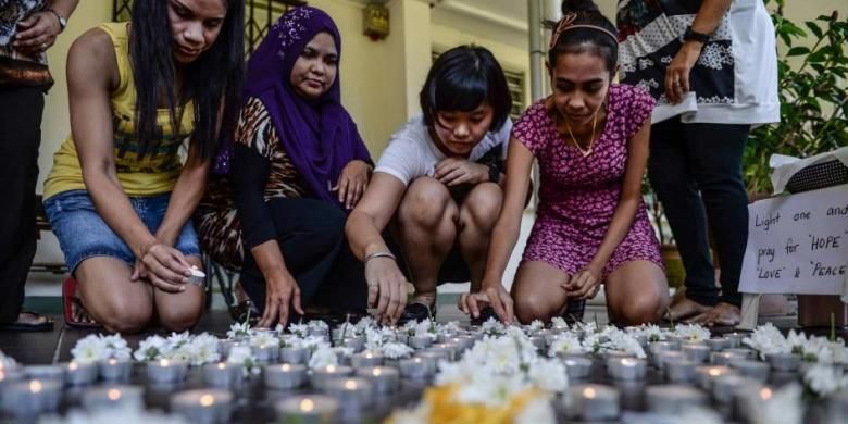 Para guru sekolah meletakkan lilin ke lantai saat acara doa bersama untuk korban hilangnya pesawat Malaysia Airlines MH370, di Petaling Jaya, Malaysia, 8 Maret 2016.