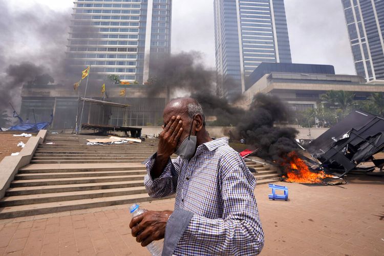 Seorang pria Sri Lanka bereaksi terhadap gas air mata saat dia berjalan melewati lokasi protes anti-pemerintah yang dirusak di luar kantor presiden di Kolombo, Sri Lanka, Senin, 9 Mei 2022. 