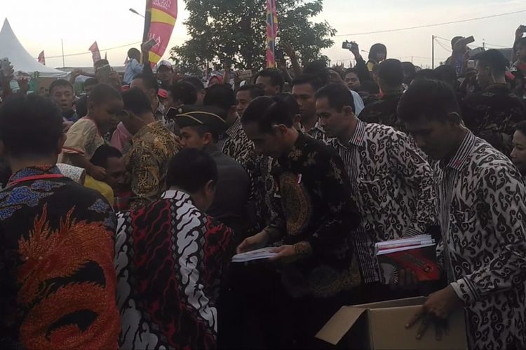 Presiden Joko Widodo membagikan buku tulis kepada warga usai meresmikan perumahan murah di Cikarang, Bekasi, Kamis (4/5/2017).