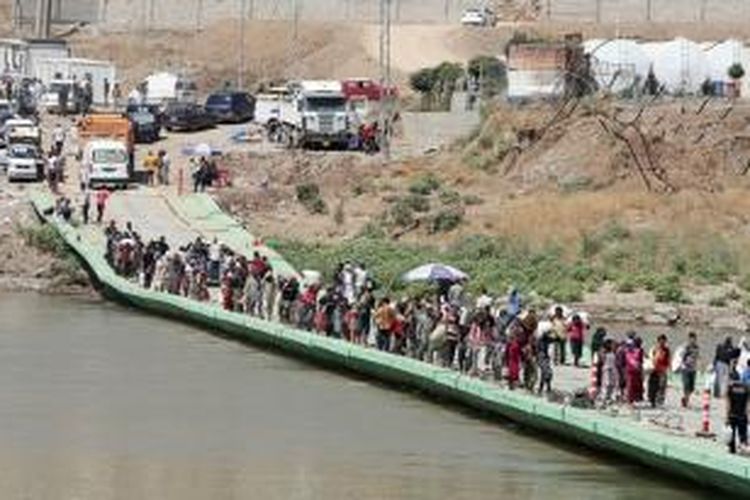 Warga etnis minoritas Yazidi melintasi perbatasan Irak-Suriah melewati jembatan Fishkhabur di Sungai Tigris. Sekitar 20.000 warga Yazidi yang terkepung di pegunungan Sinjar berhasil menyelamatkan diri ke Suriah lalu dikawal pasukan Kurdi kembali ke wilayah Irak yang aman.