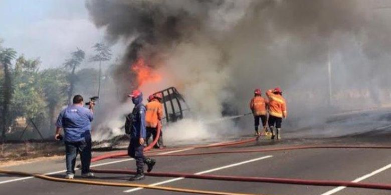 Petugas saat memadamkan api yang membakar truk bermuatan karet di jalan tol Waru - Sidoarjo 
