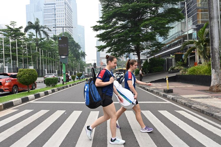 Pasangan pemain putri Ukraina, Yelyzaveta Zharka (R) and Mariia Stoliarenko, menyeberang jalan di sekitar Istora Senayan Jakarta. Gambar diambil pada 15 Juni 2022.