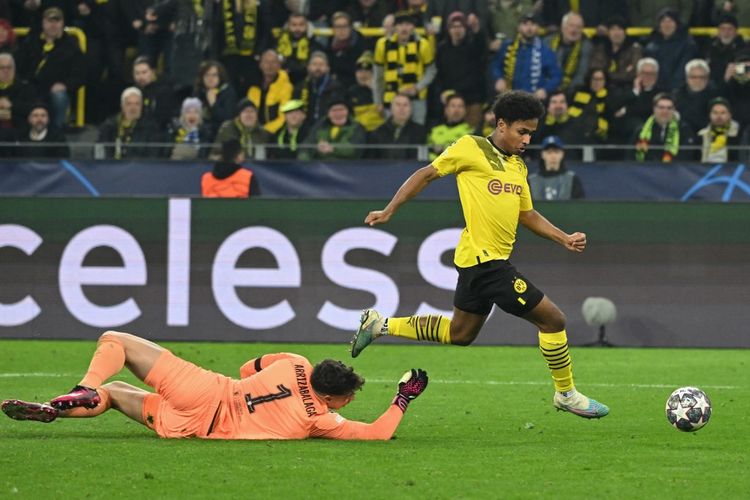 Karim Adeyemi melewati Kepa Arrizabalaga untuk mencetak gol dalam pertandingan Borussia Dortmund vs Chelsea pada leg pertama babak 16 besar Liga Champions 2022-2023 di Signal Iduna Park, Kami (16/2/2023) dini hari WIB. (Foto oleh INA FASSBENDER / AFP)