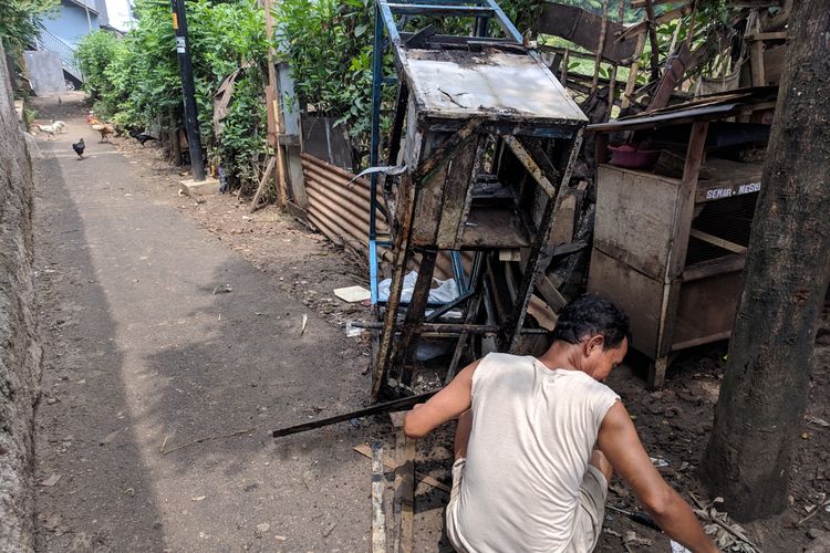 Suhendi yang sedang membongkar kayu-kayu gerobak batagornya untuk dibakar