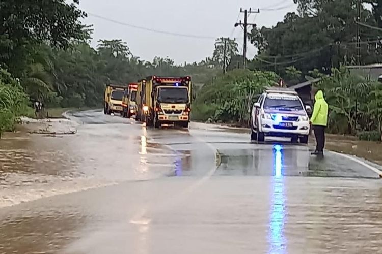 Petugas kepolisian dari Polsek Satui, Kabupaten Tanah Bumbu, Kalsel, mengatur arus lintas di Jalur Trans Kalimantan yang terendam banjir akibat tingginya intensitas hujan pada, Kamis (12/8/2021). 