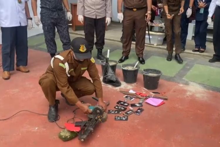 Seorang petugas Kejaksaan Negeri Ambon sedang memotong barang sitaan berupa senjata api dengan gergaji mesin di halaman kantor Kejaksaan Negeri Ambon, Senin (3/10/2022)
