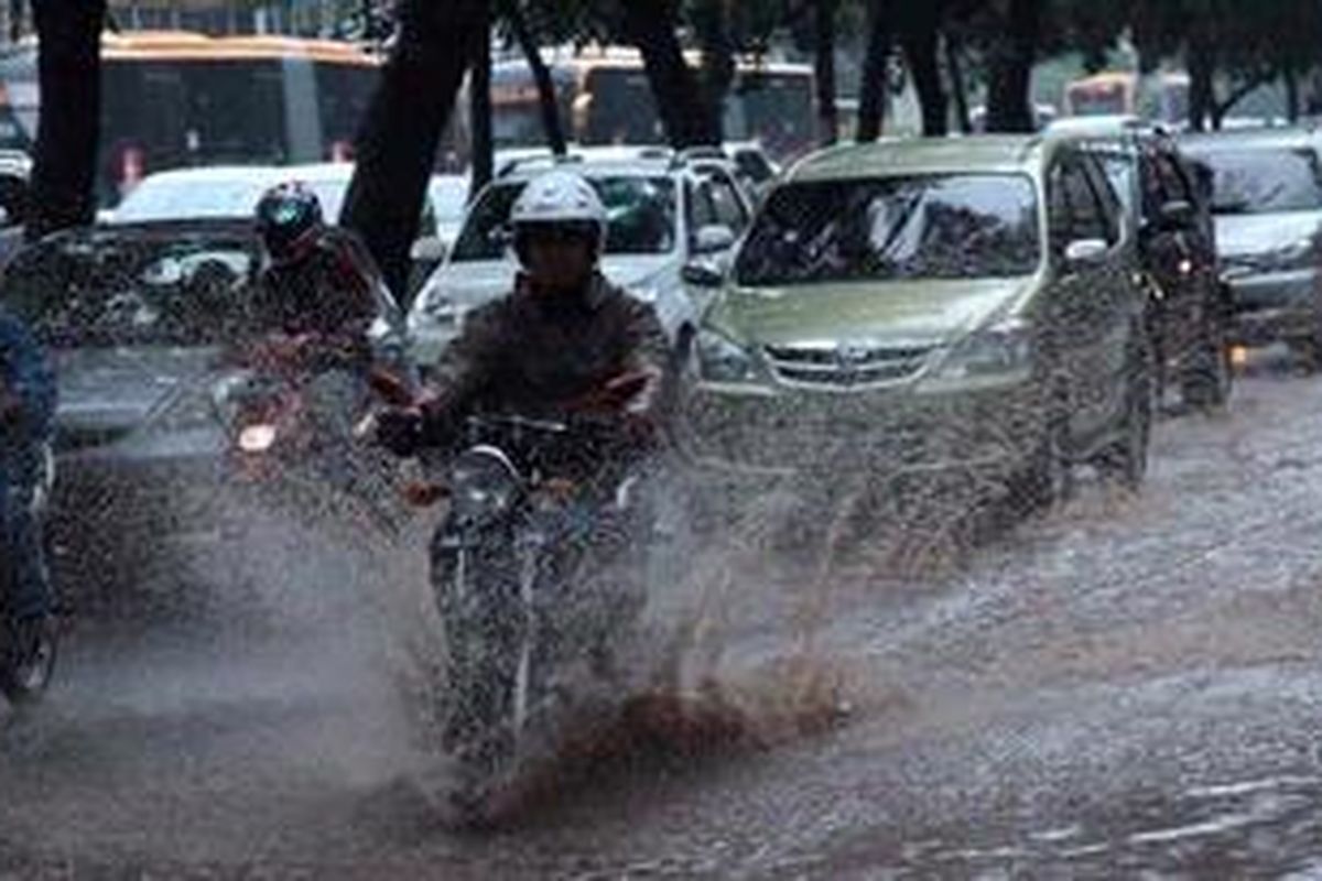 Pengguna jalan melintas di genangan air akibat hujan di Jalan Jenderal Sudirman, Jakarta selatan, Sabtu (27/4/2013). Butuh usaha ektra keras untuk membebaskan Jakarta dari genangan air akibat hujan yang turun.
