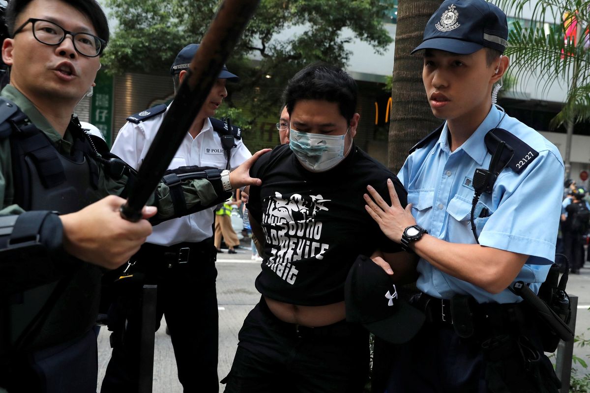 Seorang pria dikawal polisi saat pengunjuk rasa anti pemerintah dan demonstran pro China bentrok di distrik Wan Chai, saat Hari Nasional China, di Hong Kong, China, Selasa (1/10/2019).