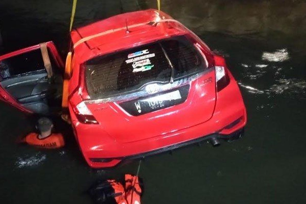 Anggota Tim Rescue PMK Surabaya menggunakan truk crane mengevakuasi mobil Honda Jazz bernopol L-1015-PB yang tercebur di sungai tengah Jalan Raya Prapen No. 266, Panjang Jiwo, Tenggilis Mejoyo, Kota Surabaya, Jumat (1/4/2022) dini hari. 