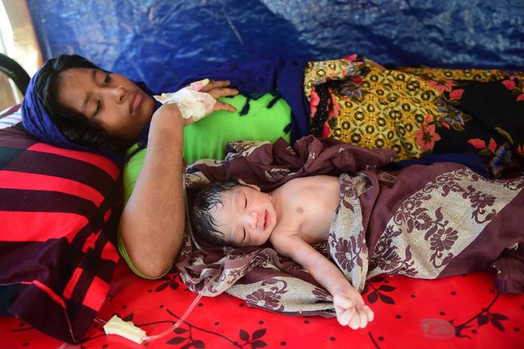 Gambar yang diambil pada 11 Oktober 2017 ini menunjukkan wanita Rohingya hamil Hasina Aktar terbaring di tempat tidur dengan bayinya yang baru lahir, Mohammed Jubayed di sebuah pusat medis di kamp pengungsi Kutupalong.