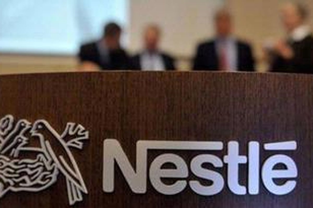 In this Feb. 19, 2010 file photo people stand behind a Nestle logo during a press conference of the food and drinks giant Nestle in Vevey, Switzerland. 