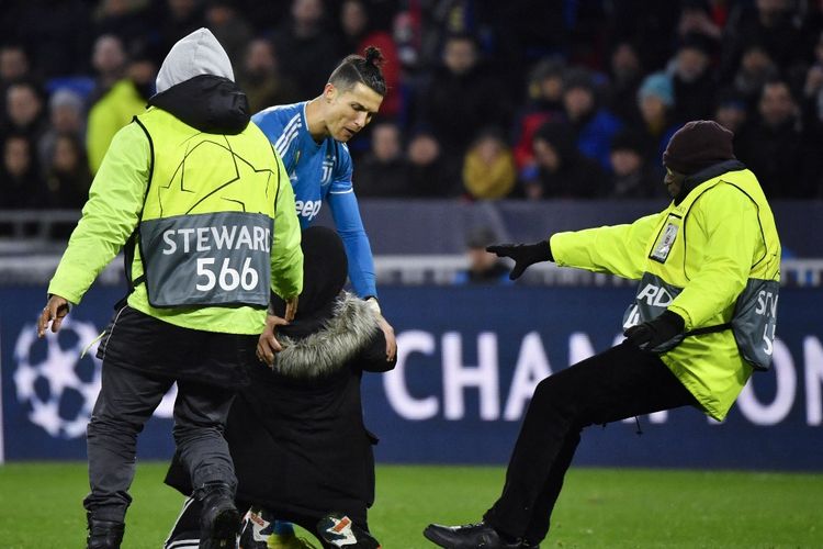 Striker Juventus Cristiano Ronaldo bereaksi ketika stewards mengawal seorang penyusup keluar lapangan dalam laga leg pertama babak 16 besar Liga Champions antara Lyon dan Juventus di stadion Parc Olympique Lyonnais di Decines-Charpieu, Prancis, Februari 26, 2020. Nantinya, peran steward akan diutamakan untuk mengamankan pertandingan di Liga Indonesia pasca-tragedi Kanjuruhan.