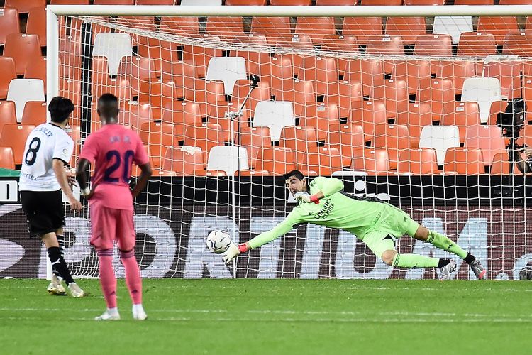 Gelandang Valencia Carlos Soler (kiri) mencetak gol penalti melewati kiper Real Madrid Thibaut Courtois dalam pertandingan Liga Spanyol antara Valencia vs Real Madrid di Stadion Mestalla di Valencia pada 8 November 2020.