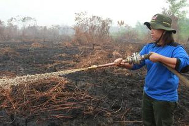 Miki Stevania, salah satu anggota Manggala Agni Daops Singkawang saat melakukan pemadaman kebakaran lahan di Desa Telok Ampening, Kecamatan Terentang, Kabupaten Kubu Raya, Kalbar (24/9/2015)