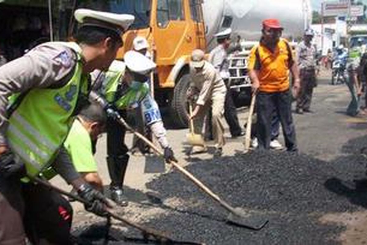 Sejumlah petugas dari Satlantas Polres Pasuruan, Jawa Timur menguruk jalan rusak tepat di Hari Valentine, Selasa (14/2/2012). Mereka berharap dapat membuat nyaman pengguna jalan. 