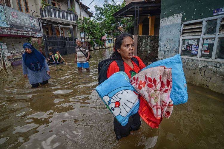 Seorang warga membawa perlengkapan tidur untuk mengungsi dari rumahnya yang terendam banjir di Kampung Bojong Asih, Dayeuhkolot, Kabupaten Bandung, Senin (12/11/2018). Banjir sedalam 1 hingga 1,5 meter tersebut disebabkan oleh luapan Sungai Citarum serta intensitas hujan yang tinggi beberapa hari terakhir di wilayah Kabupaten Bandung.