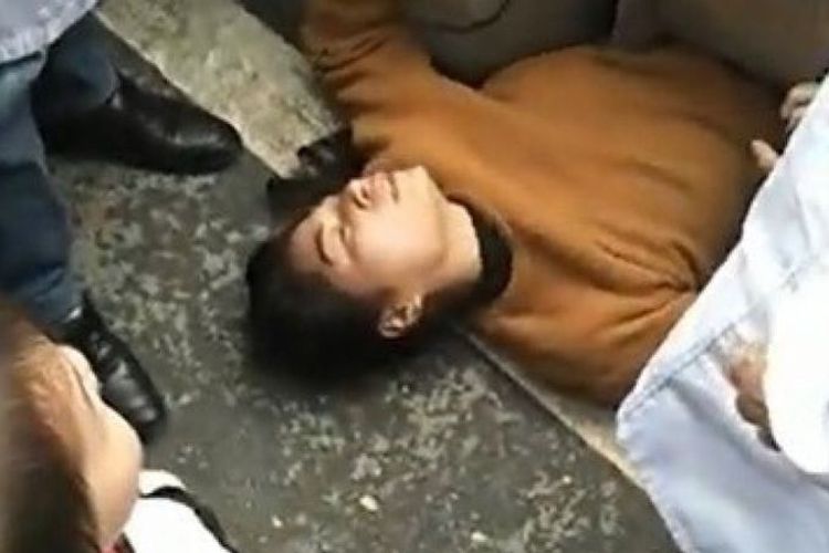 Seorang perempuan di China, Quan, berbaring di bawah mobil polisi yang akan membawa sang suami ke kantor polisi.