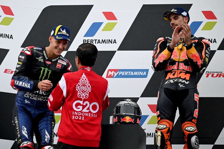 Presiden Indonesia Joko Widodo (tengah) menyerahkan trofi kepada pembalap Prancis Monster Energy Yamaha,  Fabio Quartararo (kiri) setelah balapan MotoGP Mandalika di Sirkuit Internasional Mandalika di Kuta Mandalika, Lombok Tengah, Minggu (20/3/2022).