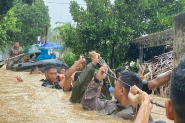 Members of the North Sulawesi Police's Mobile Brigade (Brimob) walk through flood waters after floods and landslides hit some areas in the Indonesian city of Manado in North Sulawesi, Friday, January 27, 2023.  