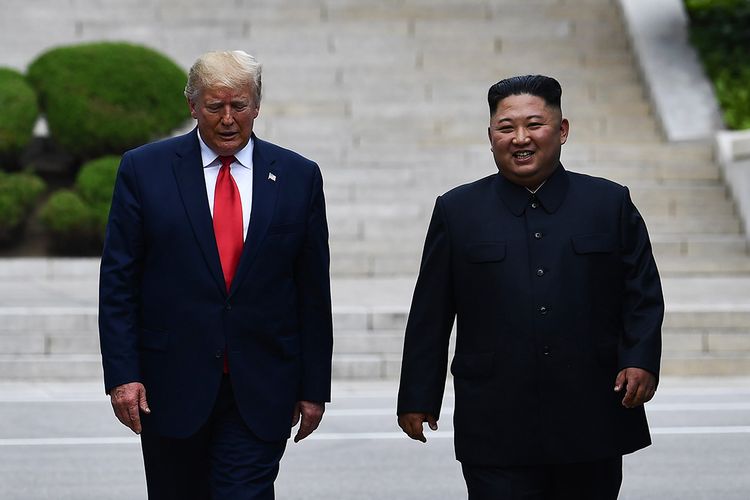 Pemimpin Korea Utara Kim Jong Un (kanan) dan Presiden AS Donald Trump berjalan bersama melintasi Garis Demarkasi Militer yang membagi Korea Utara dan Korea Selatan di zona demiliterisasi (DMZ) Korea, Minggu (30/6/2019). Kedatangan Trump ke zona demiliterisasi Korea awalnya diagendakan untuk pertemuan dengan Presiden Korea Selatan Moon Jae-in, namun Presiden Moon mengatakan fokus akan lebih kepada pertemuan Trump dengan Kim Jong Un.