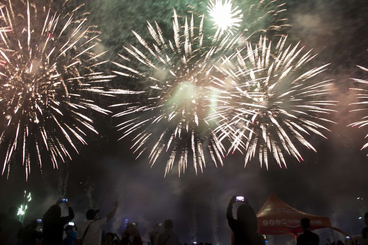 Pengunjung menyaksikan pesta kembang api terbesar The Biggest Jakarta Musical Fireworks yang digelar saat puncak malam pergantian tahun di Pantai Lagoon Ancol, Jakarta Utara (1/1/2020).Meski diguyur hutan lebat, animo masyrakat untuk merayakan tahun baru 2020 tidak surut.