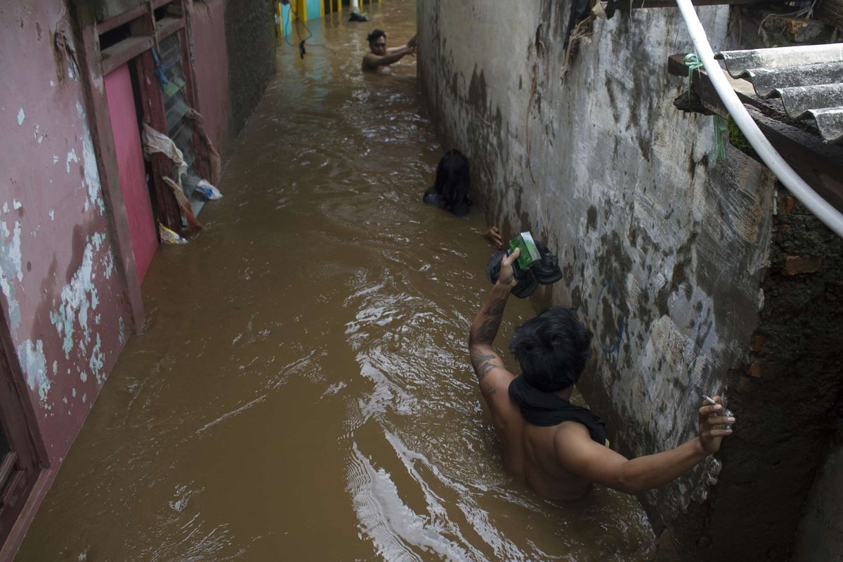 Sejumlah warga melintasi genangan banjir yang merendam wilayah Pejaten Timur, Pasar Minggu, Jakarta Selatan, Sabtu (8/2/2020). Luapan air kali ciliwung tersebut merendam pemukiman padat penduduk hingga ketinggian 2 meter.