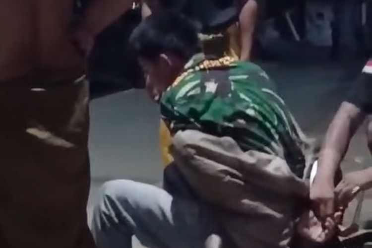 Tangkapan layar pemuda berkaos loreng saat diduga maling dan mendapatkan aksi tak terpuji oleh sekelompok orang.