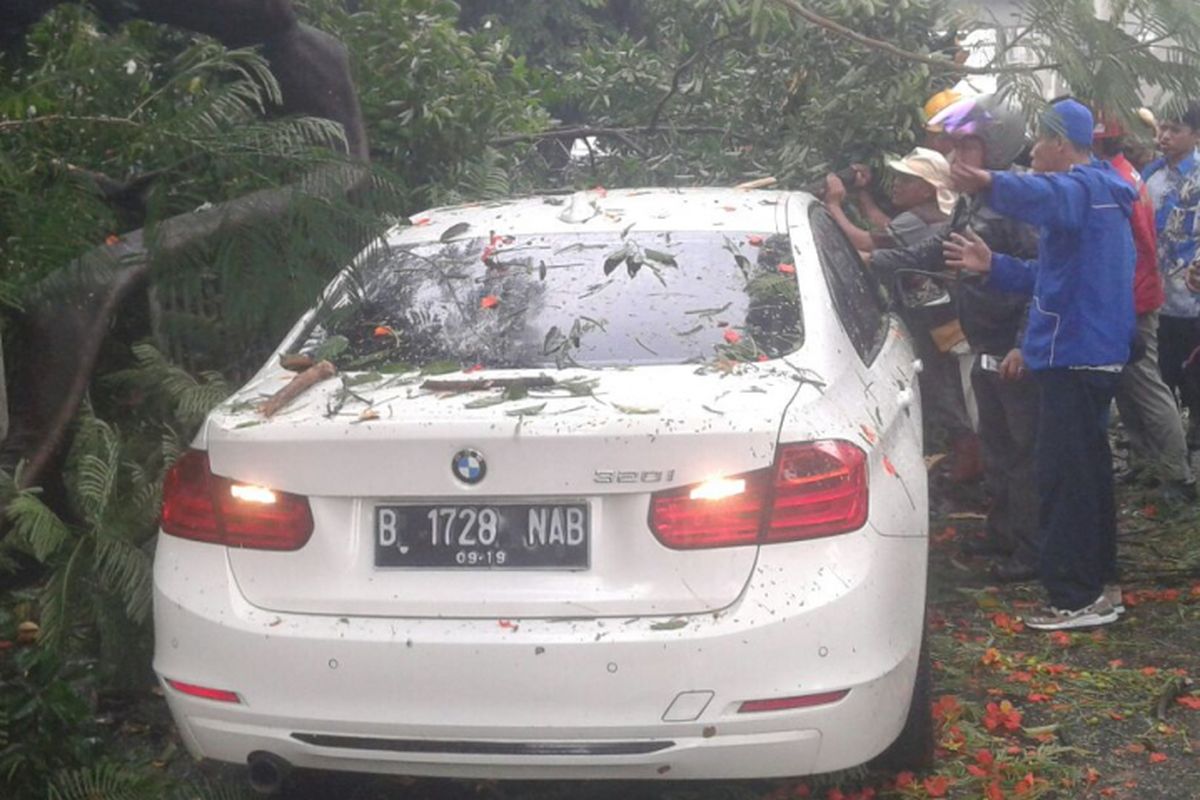 Sebuah mobil BMW putih dengan nomor polisi B 1728 NAB tertimpa pohon di Jalan Bulungan, Kebayoran Baru, Jakarta Selatan, Jumat (17/3/2017) sore.