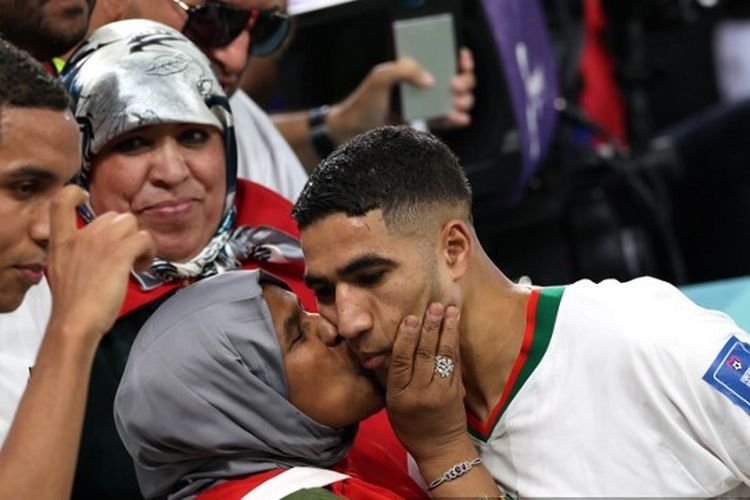 Pemain timnas Maroko, Achraf Hakimi (kanan), mendapatkan peluk dan ciuman dari sang ibu usai pertandingan Grup F Piala Dunia 2022 melawan Belgia di Stadion Al Thumama, Doha, pada Minggu (27/11/2022). Maroko berhasil mengalahkan Belgia dengan skor 2-0 pada laga tersebut. Terkini, Achraf Hakimi kembali menunjukkan rasa cinta kepada sang ibu seusai berhasil menang atas Spanyol melalui drama adu penalti di babak 16 besar Piala Dunia 2022. Pertandingan Maroko vs Spanyol berlangsung di Education City Stadium pada Selasa (6/12/2022).