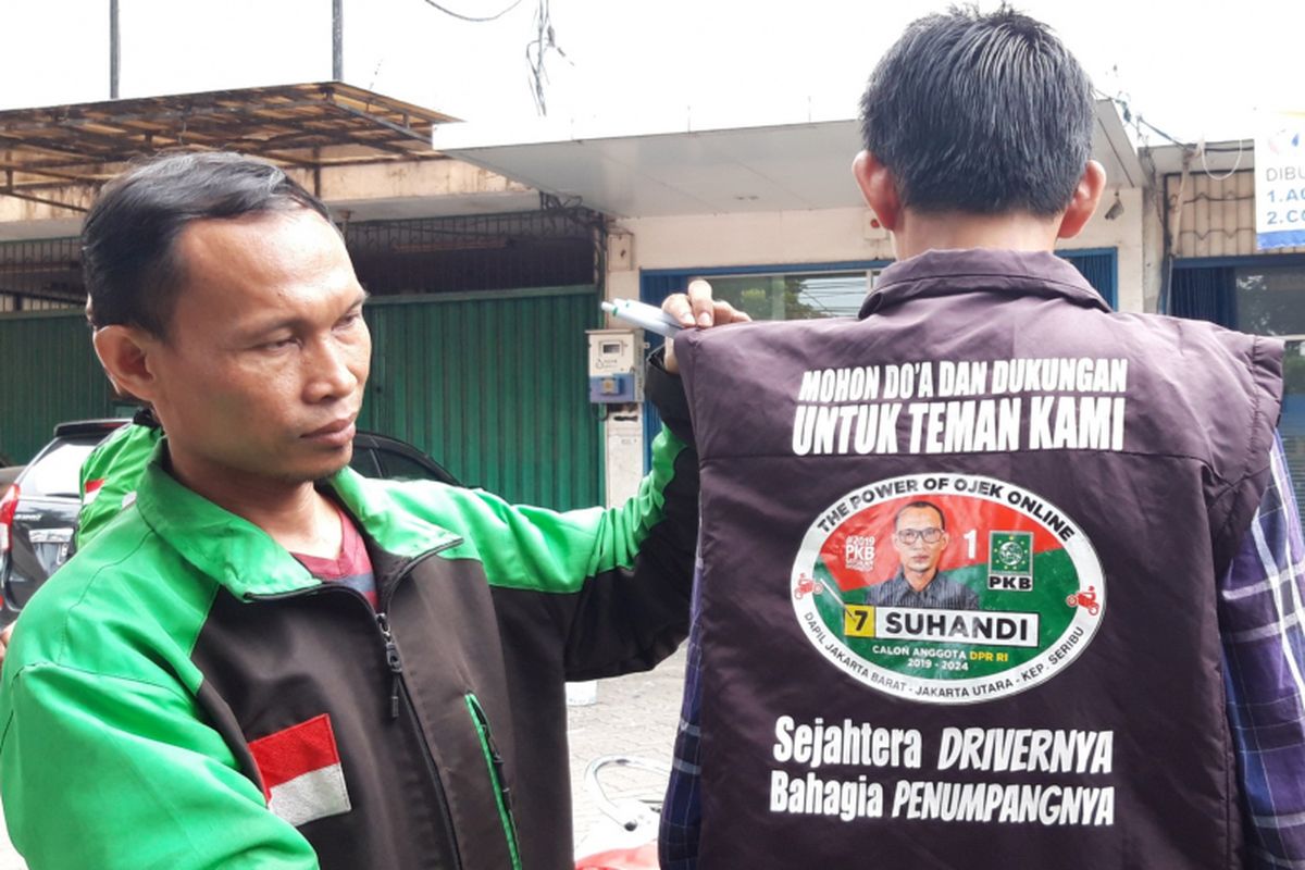 Suhandi, pengendara ojek online yang jadi caleg DPR RI dari PKB saat menunjukan rompi kampanye