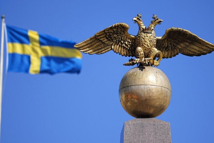 Seekor elang berkepala dua Kekaisaran Rusia terlihat di depan bendera Swedia di Batu Czarina di Market Square, di Helsinki, Finlandia, Jumat, 13 Mei 2022. 
