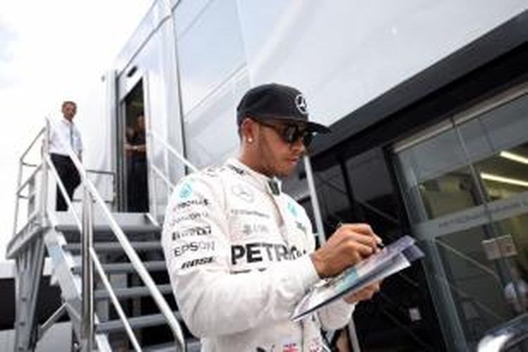 Pebalap Mercedes asal Inggris, Lewis Hamilton, memberikan tanda tangan kepada penggemar di paddock Sirkuit Silverstone pada sesi latihan ketiga GP Inggris, Sabtu (4/7/2015).