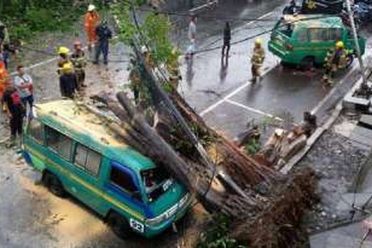Sebuah mobil angkutan kota terlihat mengalami kerusakan akibat tertimpa pohon yang tumbang di Jalan Otto Iskandar Dinata,Kota Bandung, Minggu (13/11/2016). 