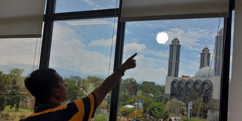 Seorang sedang menunjuk kaca gedung milik Universitas Negeri Padang (UNP), yang bolong atau berlubang akibat diduga peluru nyasar, Selasa (25/2/2020). 