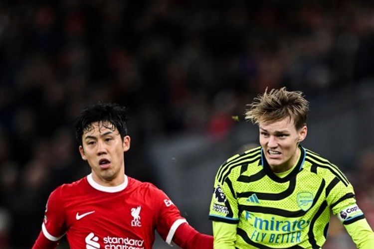 Gelandang Arsenal, Martin Odegaard, tengah menatap bola bersama dengan pemain Liverpool, Wataru Endo, dalam lanjutan Premier League 2023-2024 antara Liverpool vs Arsenal di Stadion Anfield pada 23 Desember 2023.