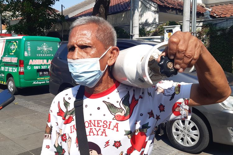 Suharto, warga Pucangsawit, Jebres, Solo sambil memanggul tabung oksigen yang dia isikan ulang secara gratis di halaman Rumah Dinas Wali Kota Loji Gandrung Jalan Slamet Riyadi Solo, Jawa Tengah, Sabtu (31/7/2021).