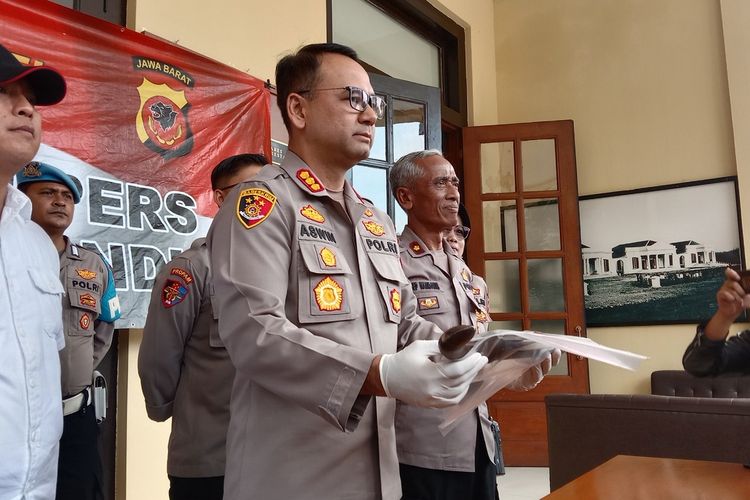 Kapolrestabes Bandung Kombes Aswin Sipayung tengah memperlihatkan barang bukti golok yang digunakan pelaku untuk menganiaya temannya gara-gara rebutan lahan parkir.