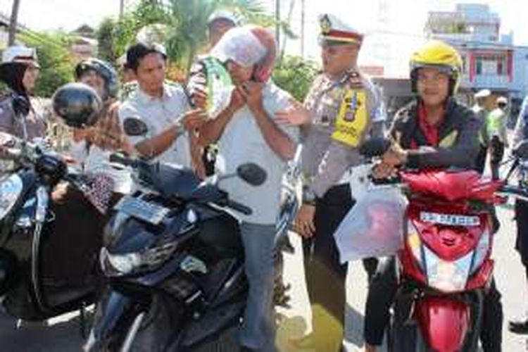 Pengendara motor yang taat berlalu lintas di Meulaboh, Aceh Barat, mendapatkan helm gratis dari [polisi setempat.