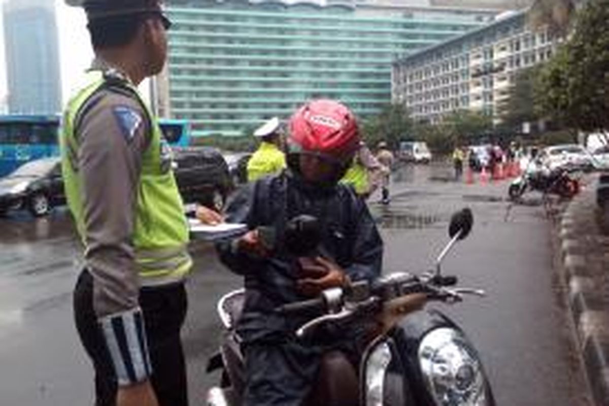 Saah seorang pengendara motor ditilang karena mencoba menerobos jalur pelarangan sepeda motor di Jalan M.H Thamrin, Jakarta Pusat, Senin (19/1/2015).