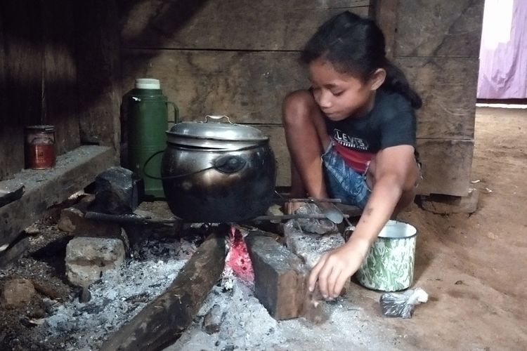 Karolina Verawati (11), seorang anak yatim piatu di kampung Racang, Desa Colol, Kecamatan Lambaleda Timur, Kab. Manggarai Timur, NTT sedang masak nasi di dapurnya, Kamis, (27/1/2022). (KOMPAS.com/MARKUS MAKUR)