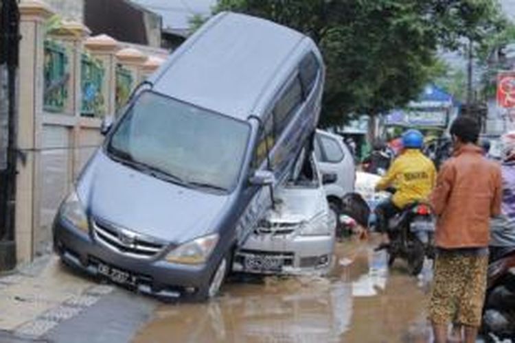 Sejumlah mobil di kota Manado, Sulawesi Utara, Kamis (16/1/2014), masih dalam posisi tumpang tindih setelah terhantam banjir bandang.