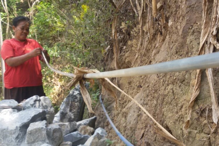 Seniyem (45 tahun), warga Dusun Crangah, Desa Hargotirto, Kulon Progo, Daerah Istimewa Yogyakarta. Ia memeriksa selang 1,2 kilometer miliknya yang direntangkan untuk mengalirkan air bersih dari mata air di bukit ke rumahnya di lereng.