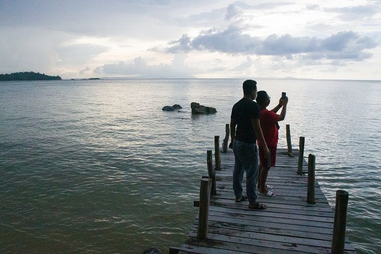 Dua orang wisatawan sedang menikmati pemandangan matahari dan hamparan laut lepas di area dermaga tepi pantai di Kasuari Valley Beach Resort di Kota Sorong, Papua Barat, Senin (25/10/2021).